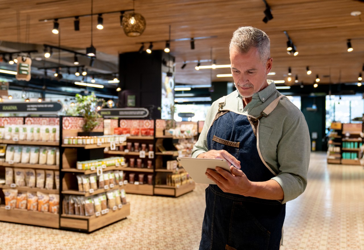 Portrait of a Latin American retail clerk working at the supermarket using a digital tablet